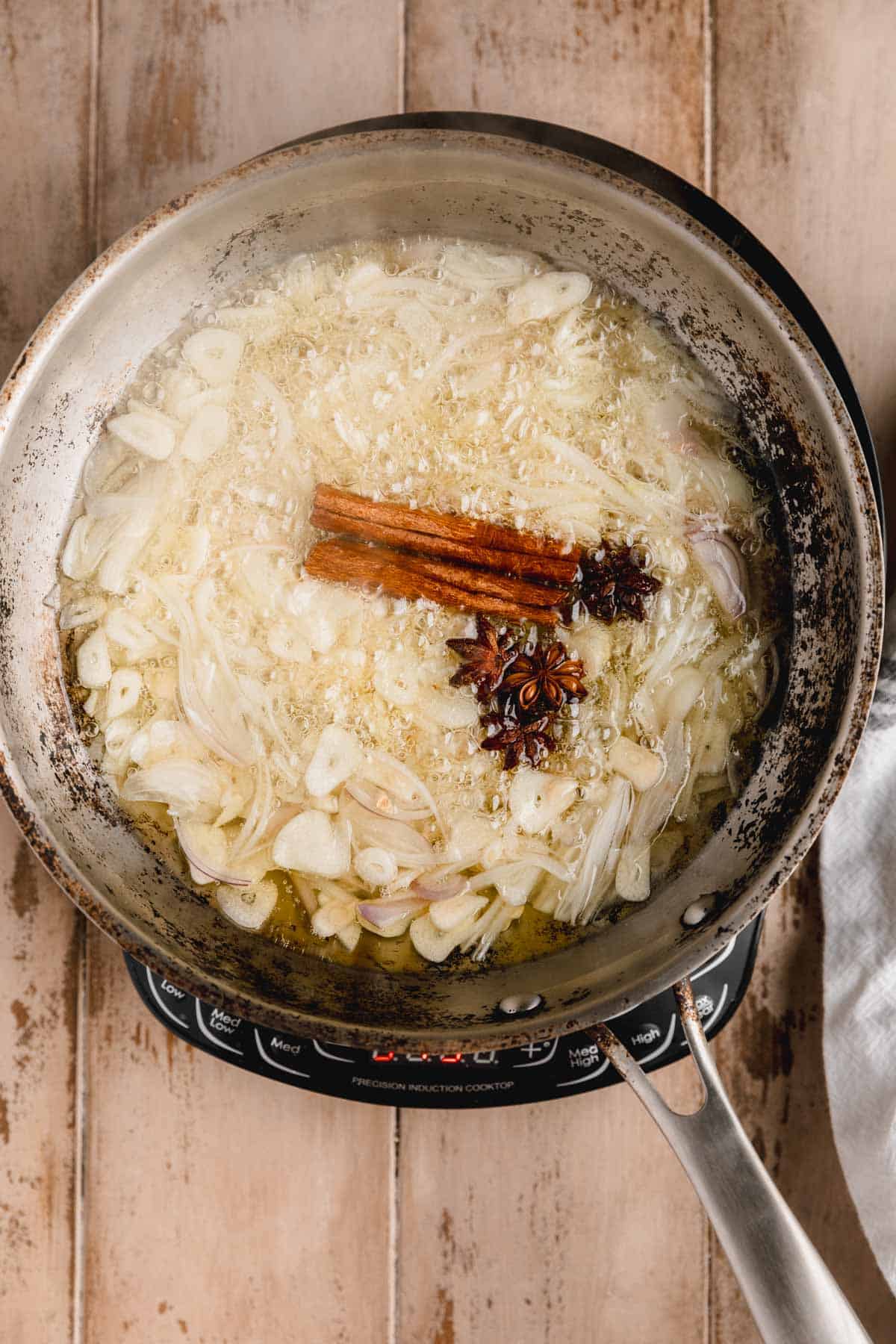 Shallots, garlic, cinnamon and star anise cooking in a sauté pan.