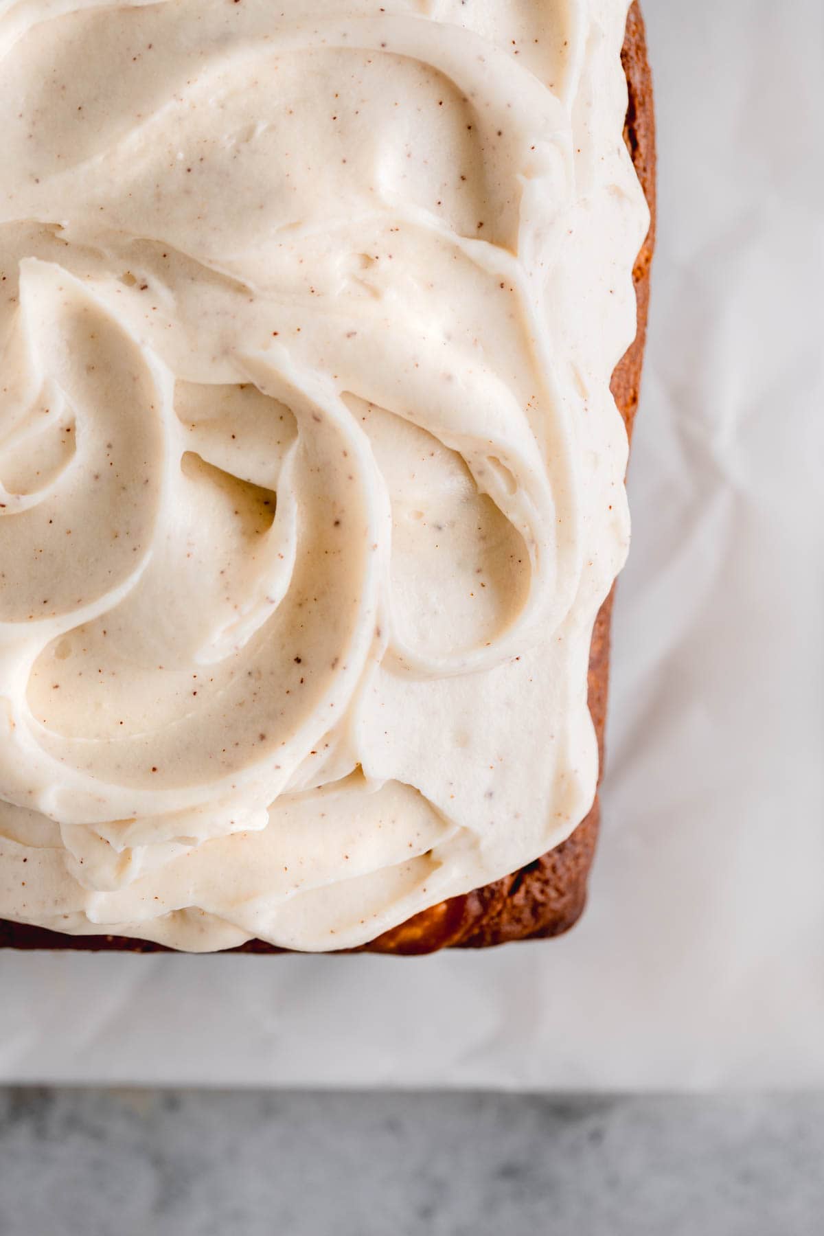 Cream cheese frosting spread on top of pumpkin bread.