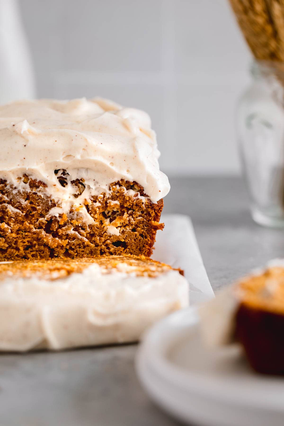 Pumpkin bread with cream cheese frosting, partially sliced.