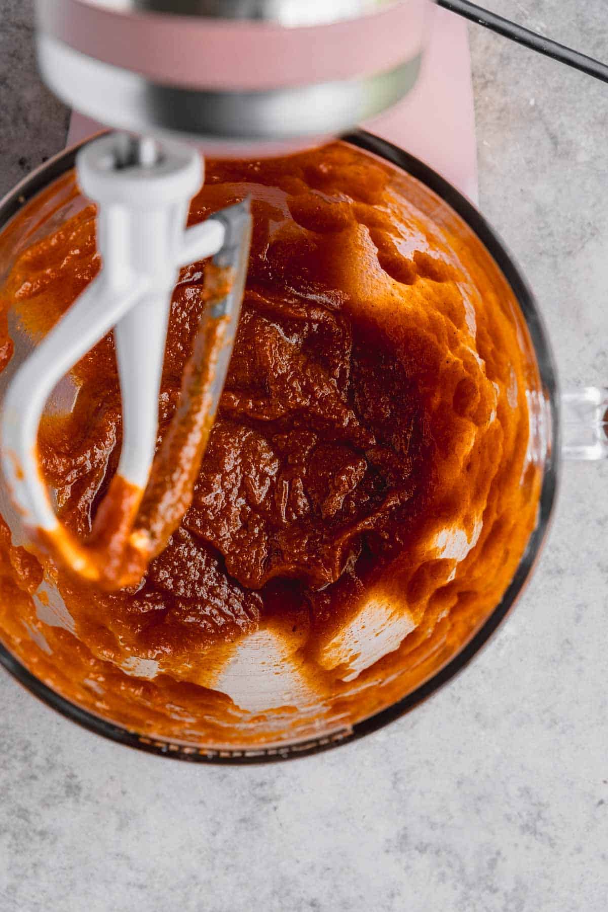 Pumpkin puree mixed with sugar and oil in the bowl of a stand mixer.