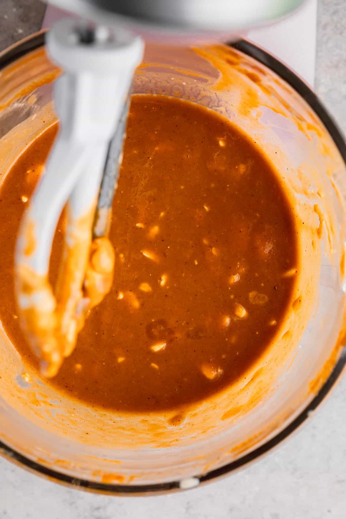 Cream cheese, vanilla and milk mixed into batter in bowl of a stand mixer. 