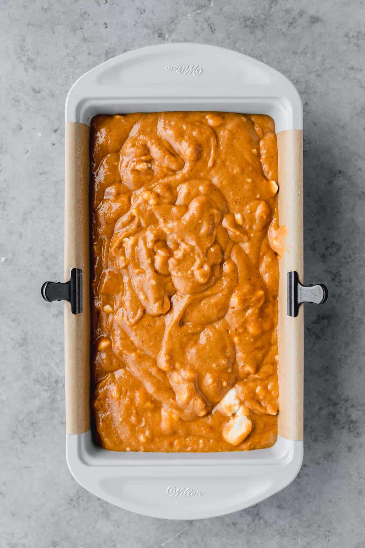 Pumpkin bread batter poured into a loaf pan prepared for baking. 