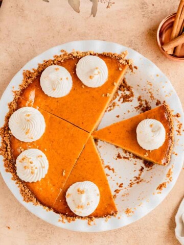 Pumpkin Pie with Graham Cracker crust in a pie dishes with a few slices removed.