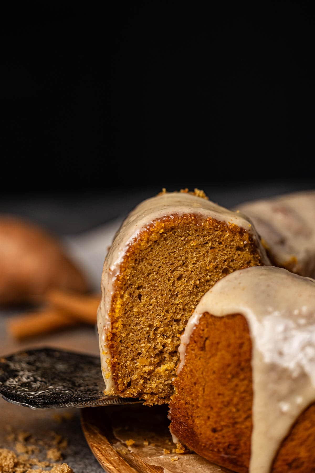 A slice of Sweet Potato Pound Cake topped with marshmallow glaze cut and being lifted. 