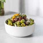 Marinated olives in a bowl with rosemary and orange peel.
