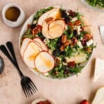 Arugula Pear Salad in a bowl topped with nuts and sherry dressing.