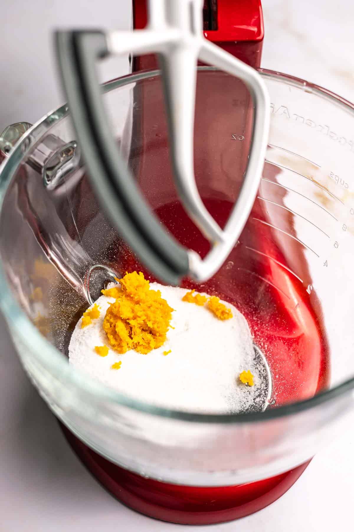 Sugar and orange zest in the bowl of a stand mixer.