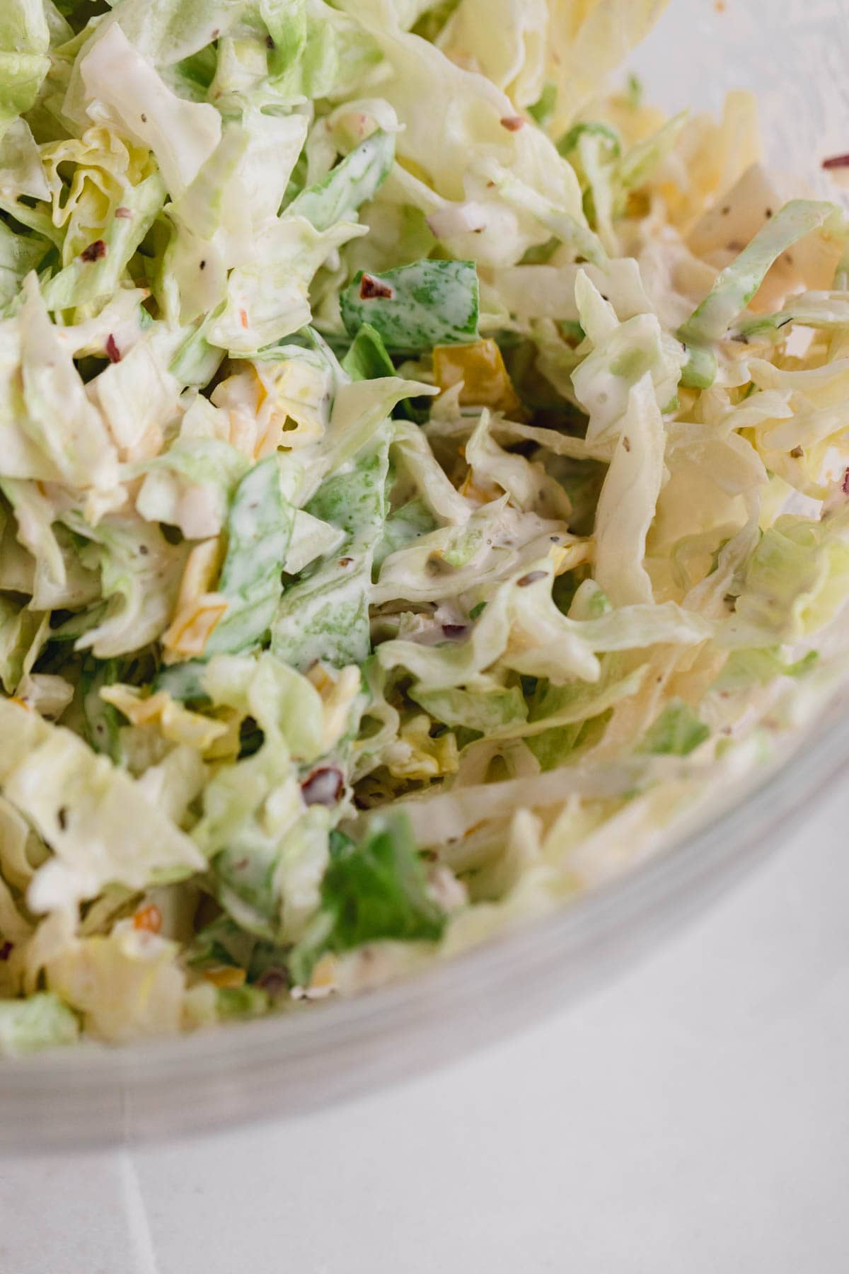 Shredded lettuce in a bowl with dressing. 