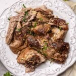 Braised pork shoulder on a plate shredded into larger chunks.