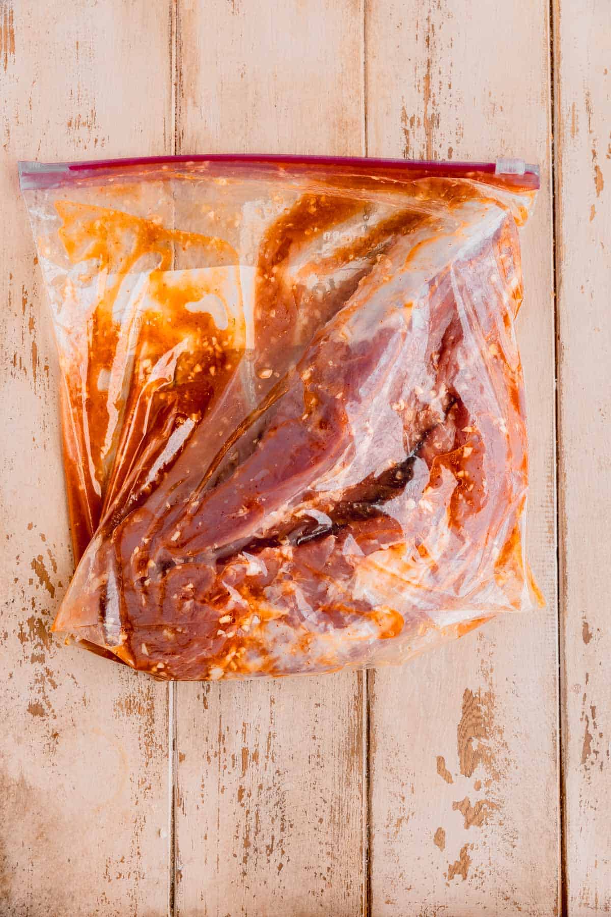 Pork tenderloin marinating in a plastic bag.