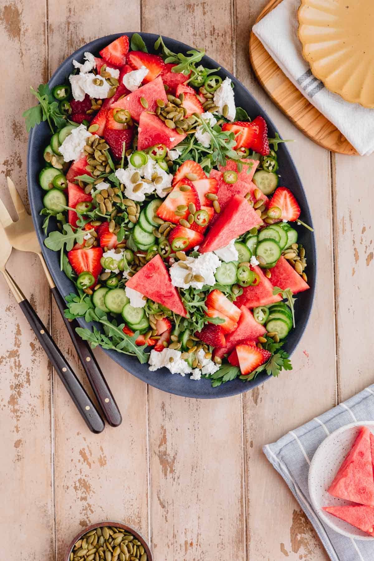 Spicy Watermelon Arugula Salad topped with goat cheese and strawberry vinaigrette on a large serving platter.
