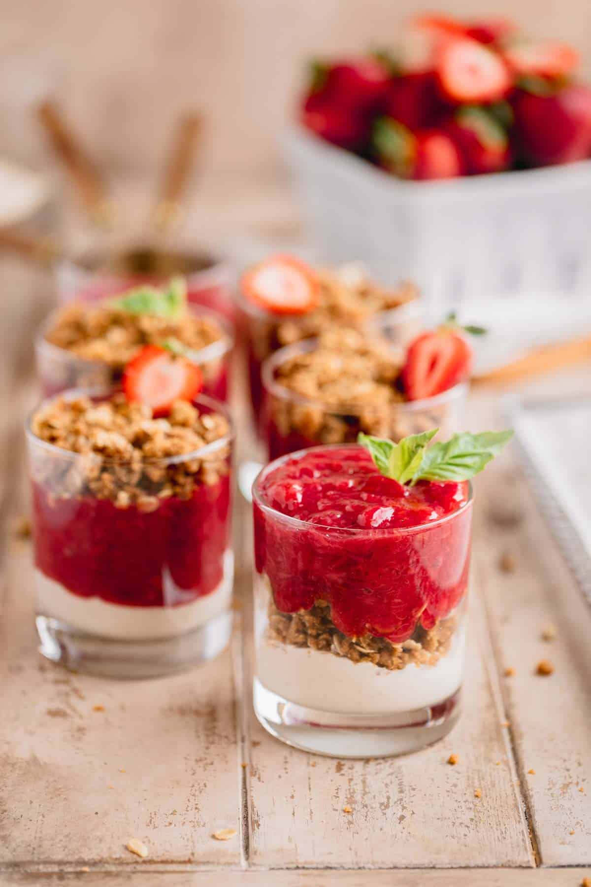 Strawberry Rhubarb Crumble in individual portion cups on a wooden table.