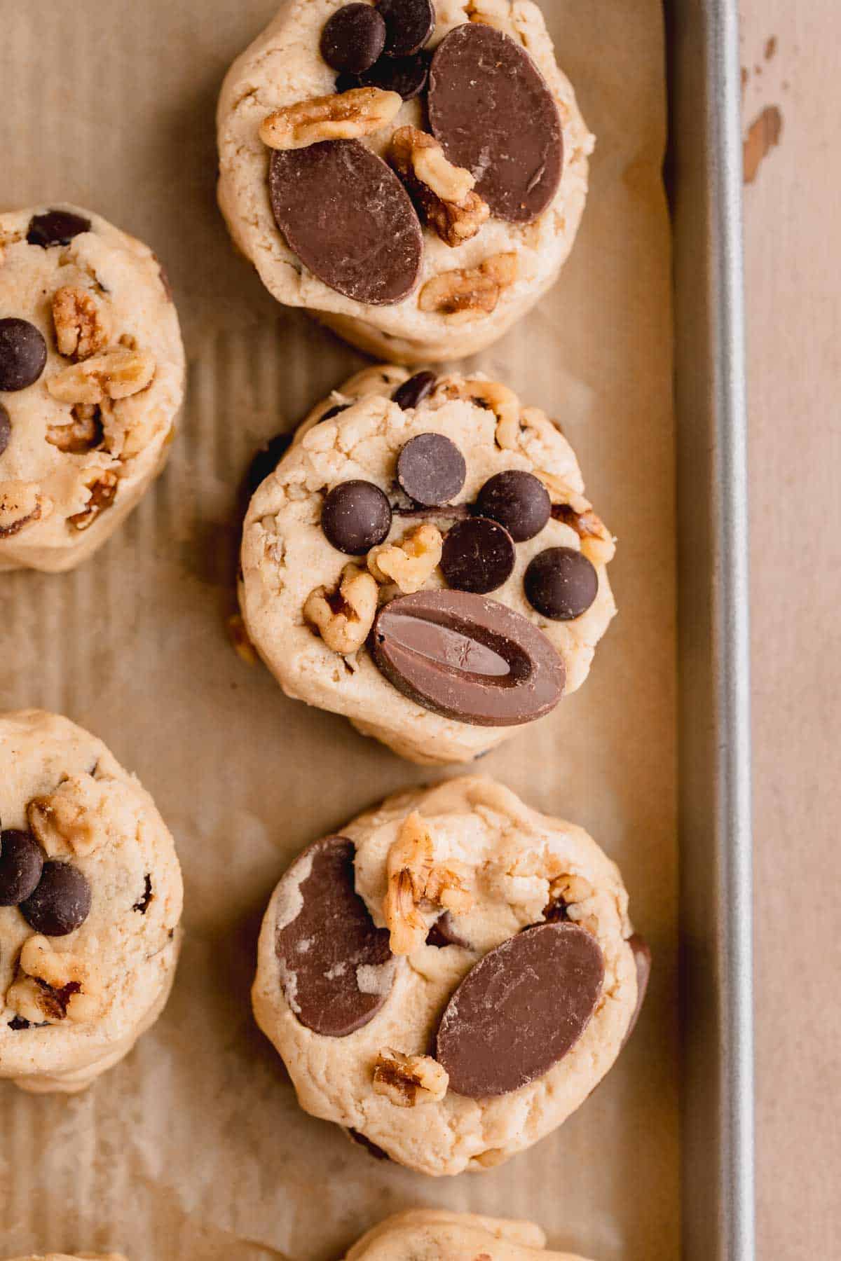 Cookie dough scooped into 4 oz balls then formed flat on top and placed on a parchment lined sheet tray. 