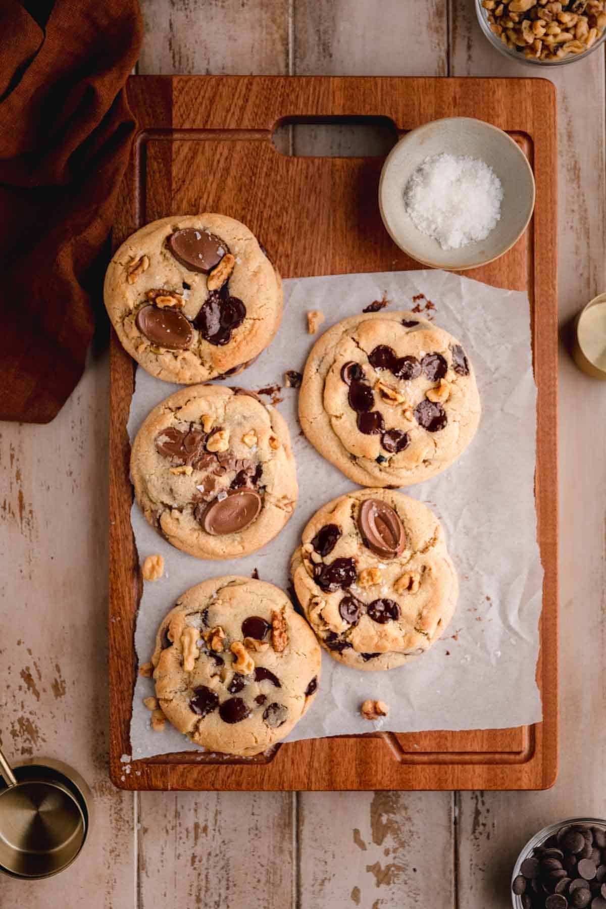 Walnut Chocolate Chip Cookies on a board with flaky sea salt.