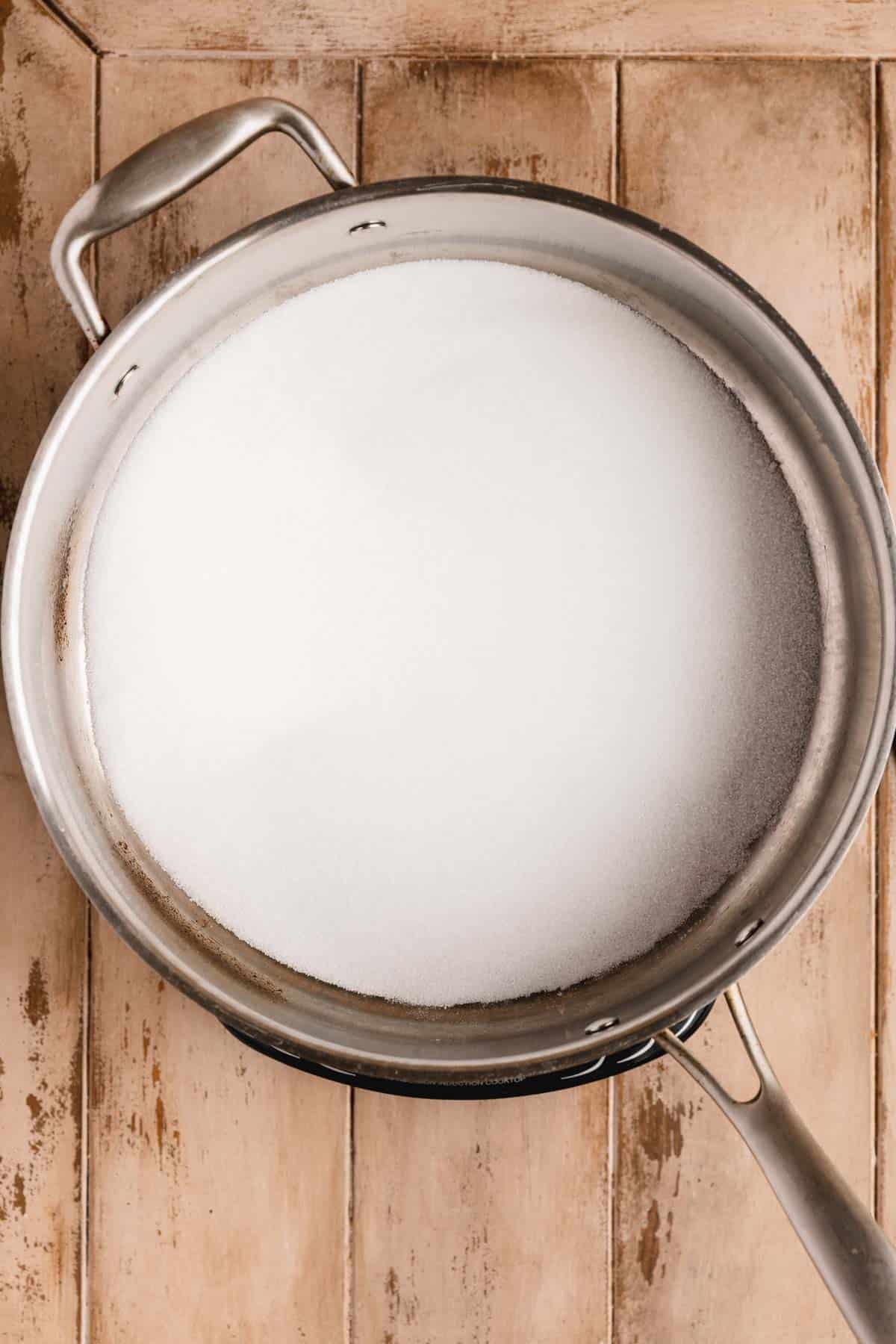 Evenly spread sugar in the bottom of a large heavy bottomed pan.