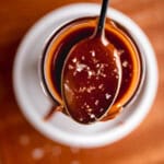 Quick Caramel Sauce on a spoon topped with flaky sea salt.