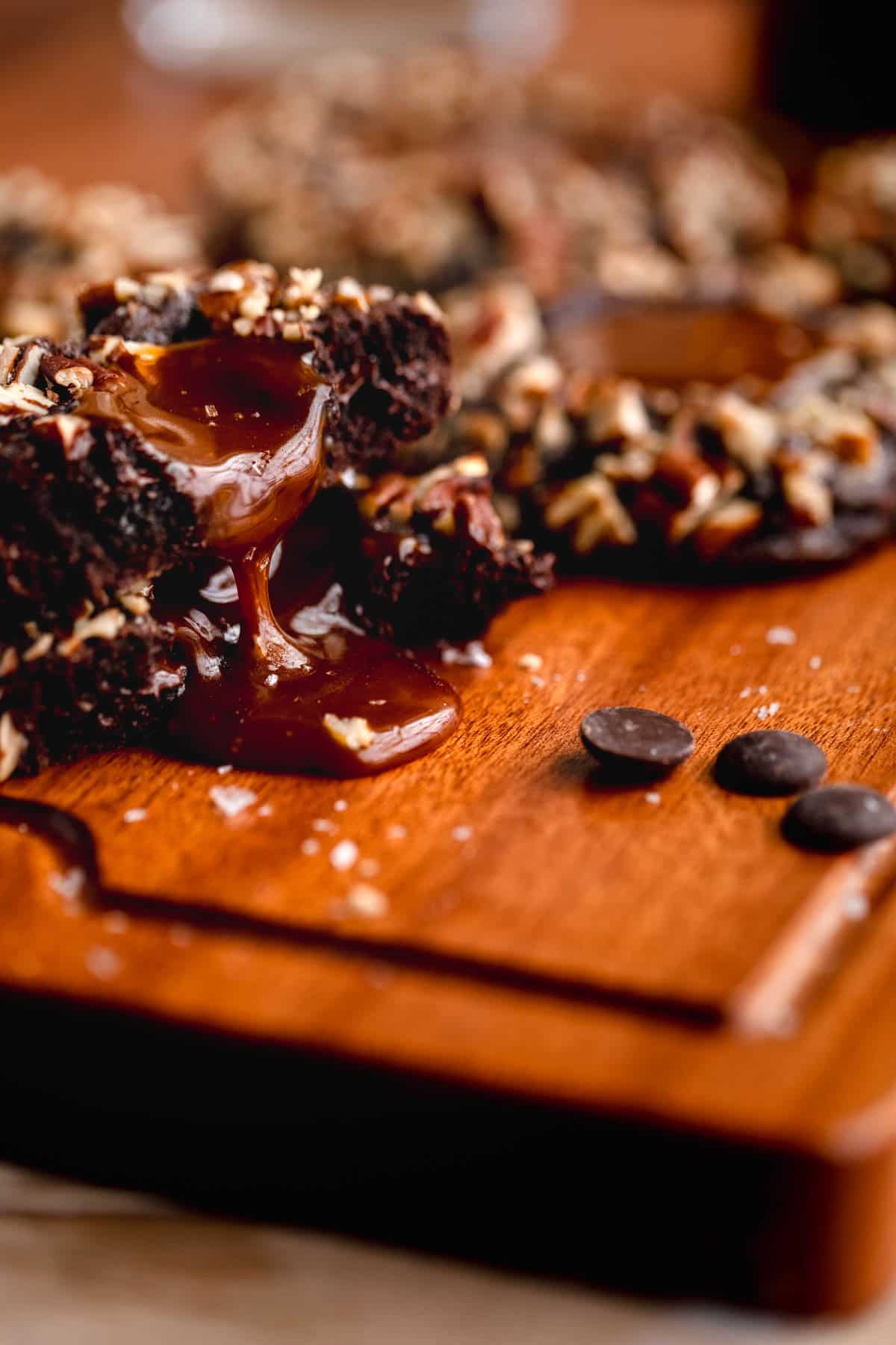 A Turtle Cookie broken in half and stacked with the caramel center dripping down on a cutting board.