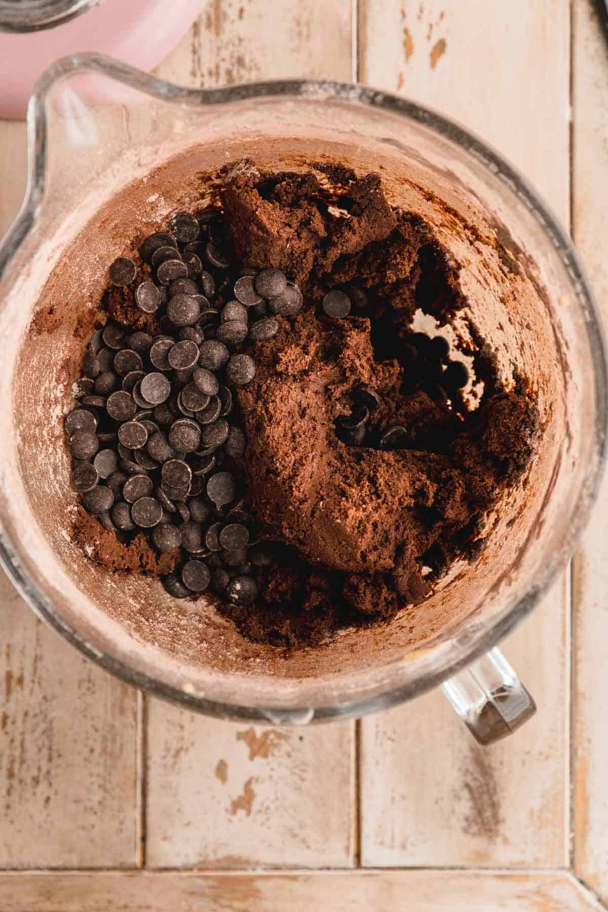 Chocolate chips being added to chocolate cookie dough.