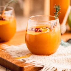 Mulled Apple Cider in a glass with orange slices, cinnamon sticks and pomegranate.