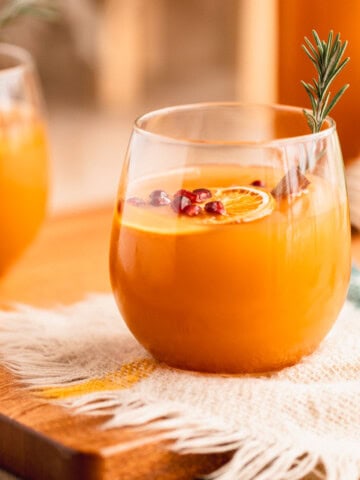 Mulled Apple Cider in a glass with orange slices, cinnamon sticks and pomegranate.