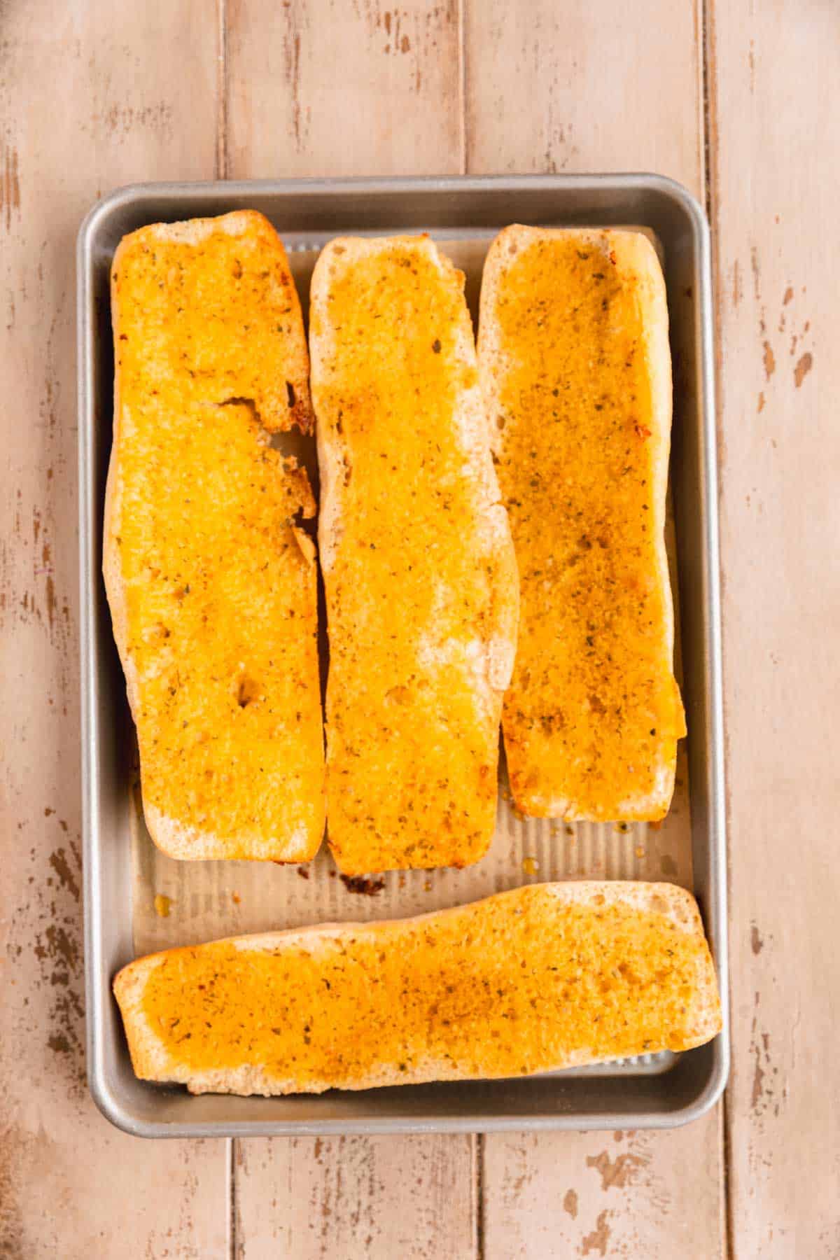Toasted garlic bread on a sheet tray.