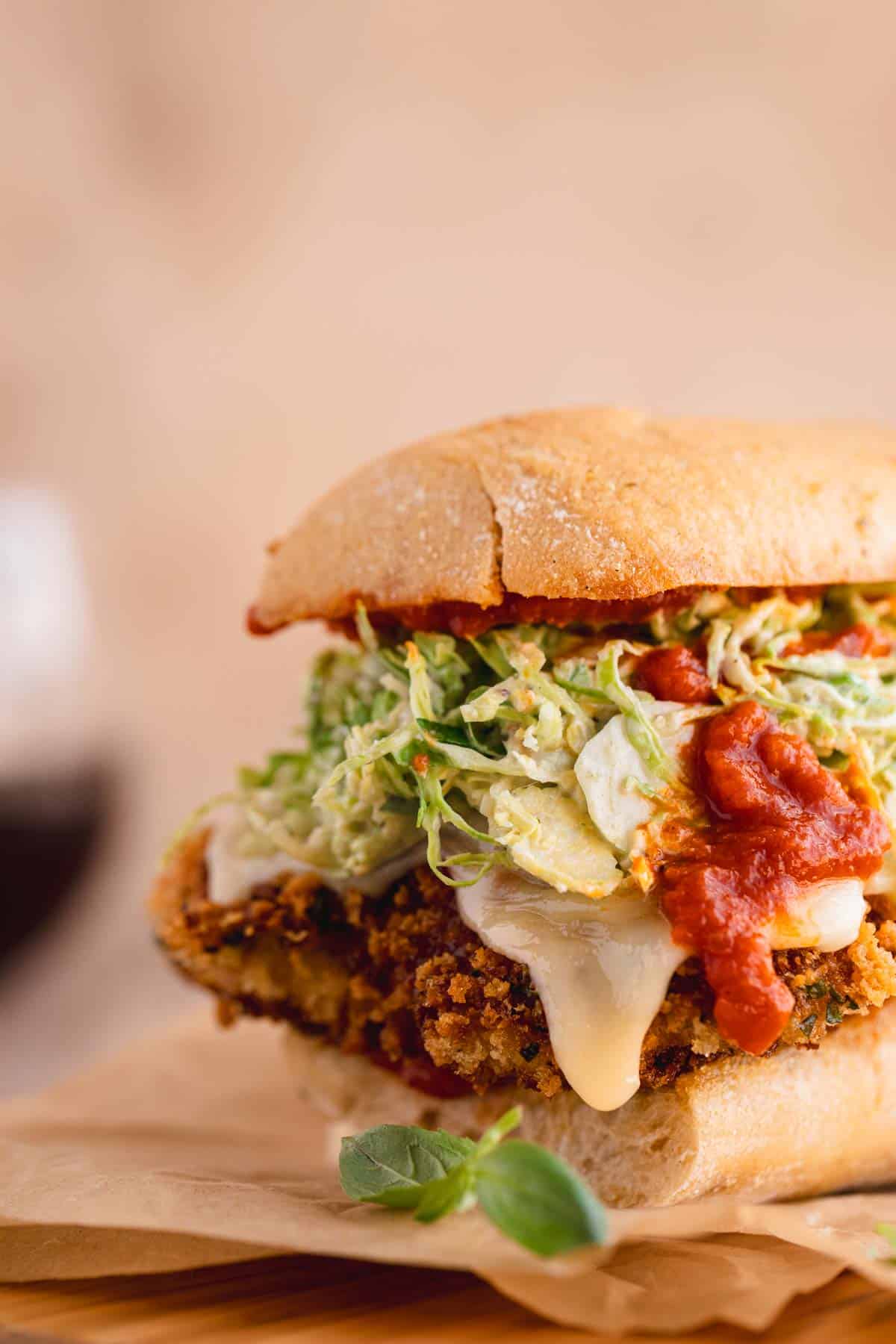 Chicken Parmesan Sandwich on garlic bread topped with Brussel Sprout Caesar Salad.