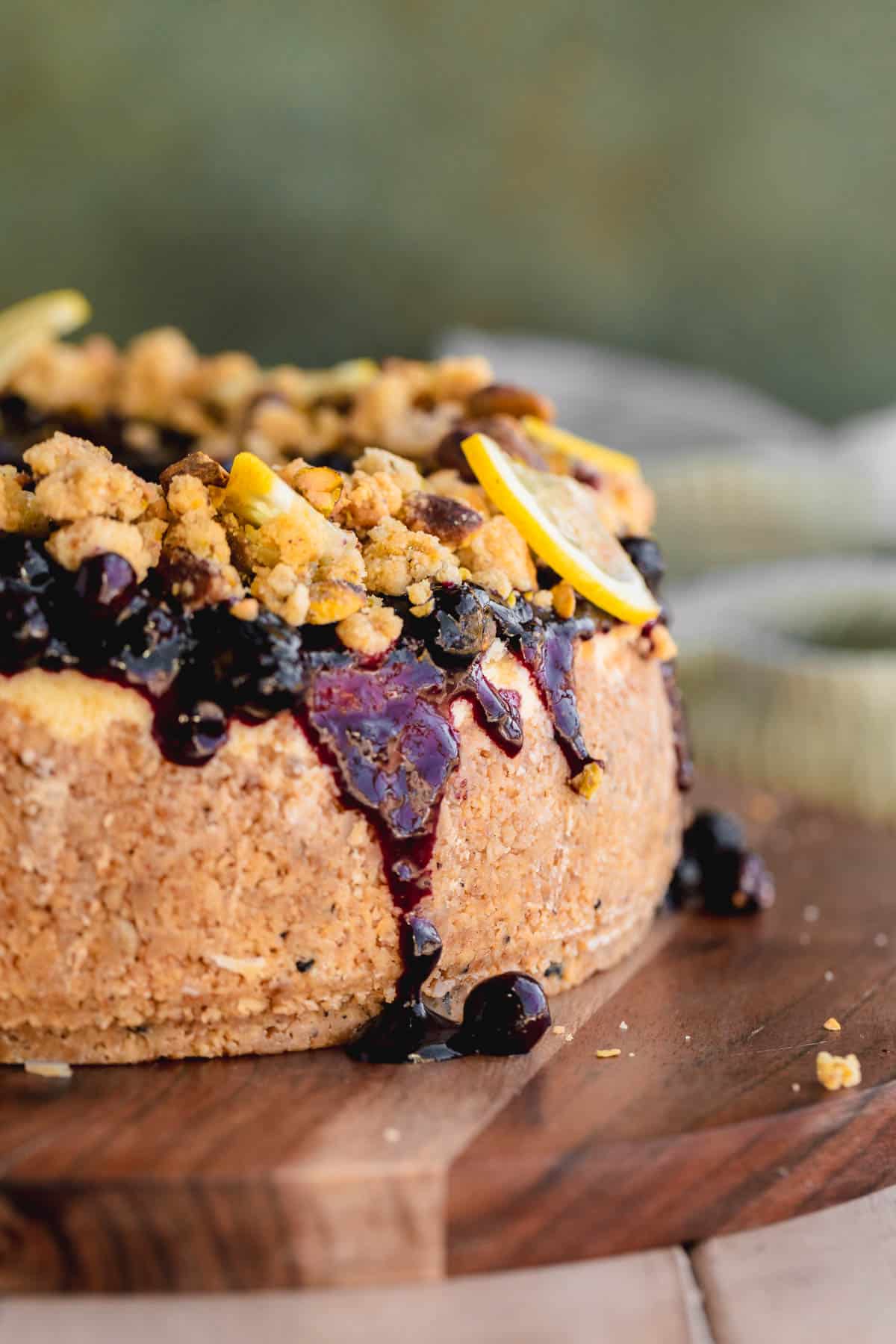 Lemon Blueberry Cheesecake topped with blueberry compote and pistachio crumble with lemon slices. 