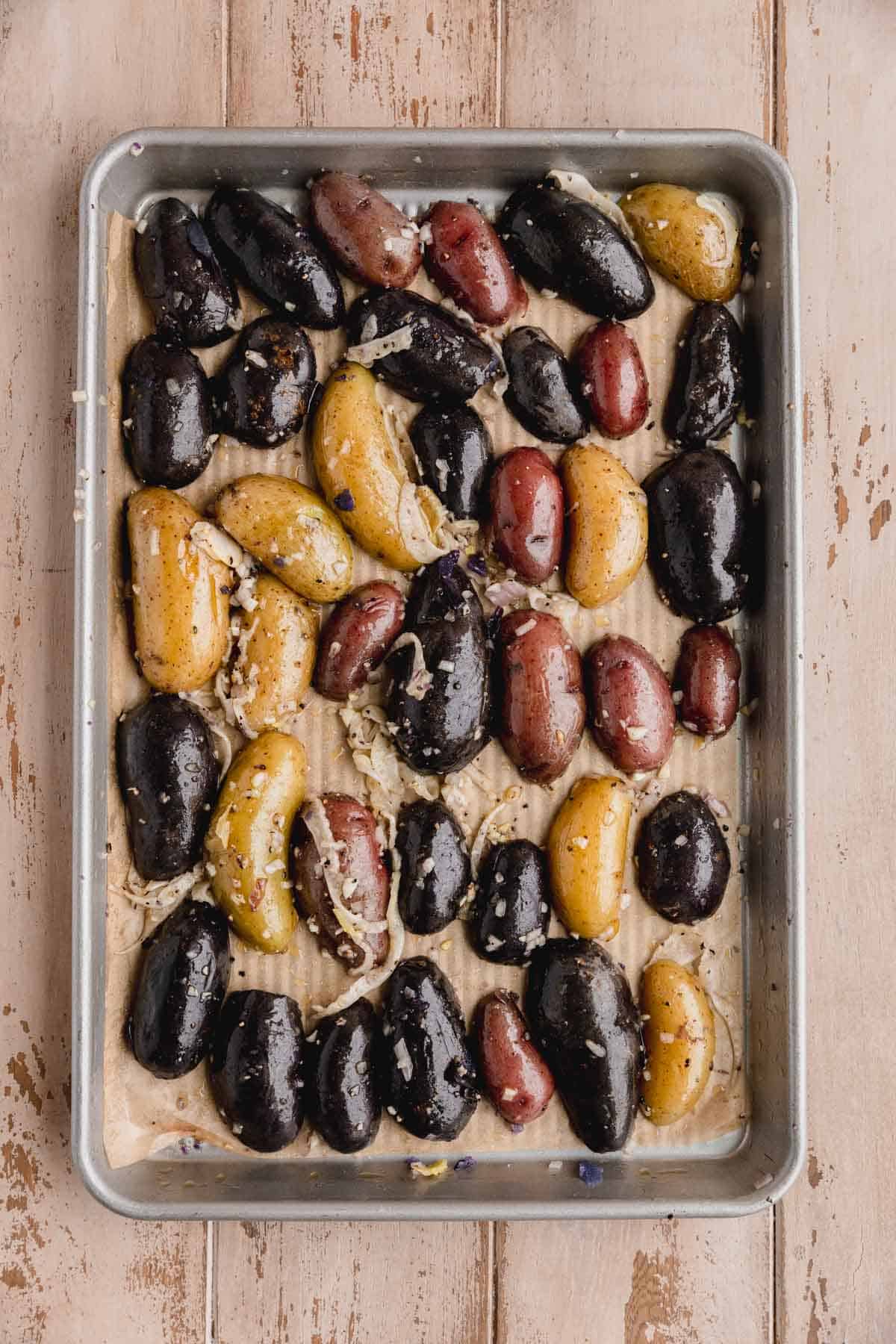 Oiled and seasoned fingerling potatoes on a tray right before being roasted.