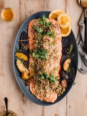 Mediterranean Citrus Roasted Salmon with Olive Relish on a serving platter with potatoes.