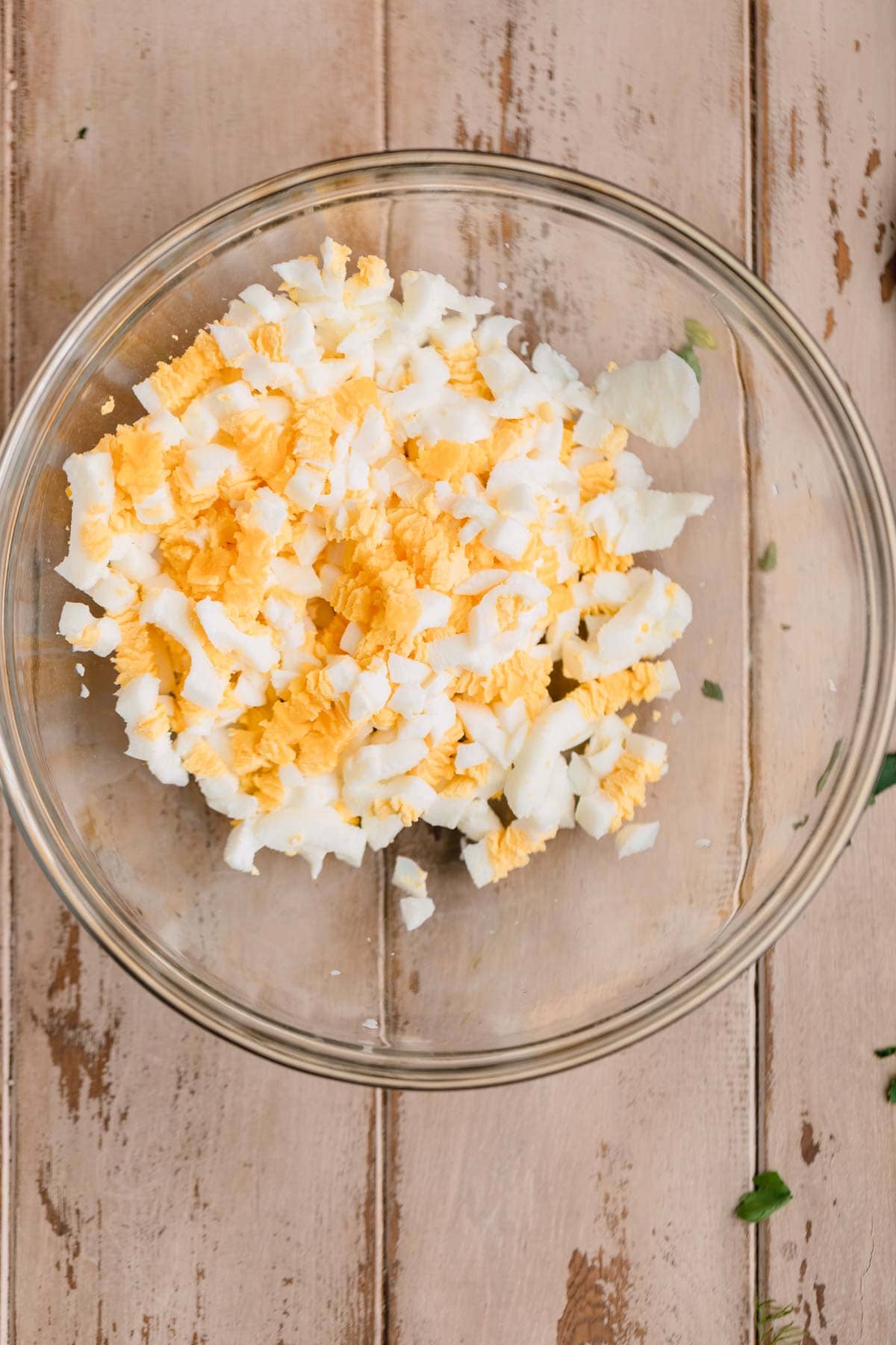 Hard boiled eggs pushed through a wire cooling rack into a bowl.