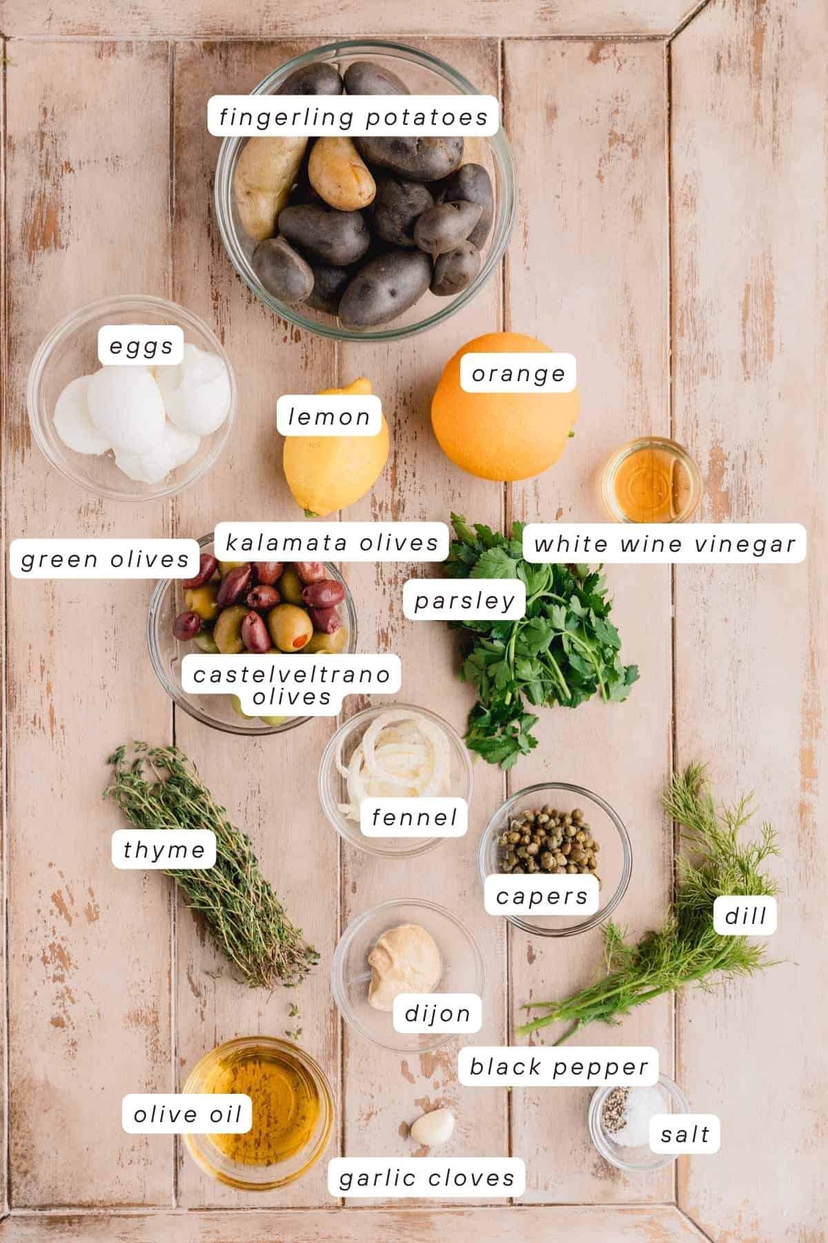 Fingerling potatoes, orange, lemon, eggs, white wine vinegar, parsley, dill, capers, salt, pepper, garlic clove, dijon, fennel, olive oil, thyme, green olives, kalamata olives, castelvetrano olives, and eggs.