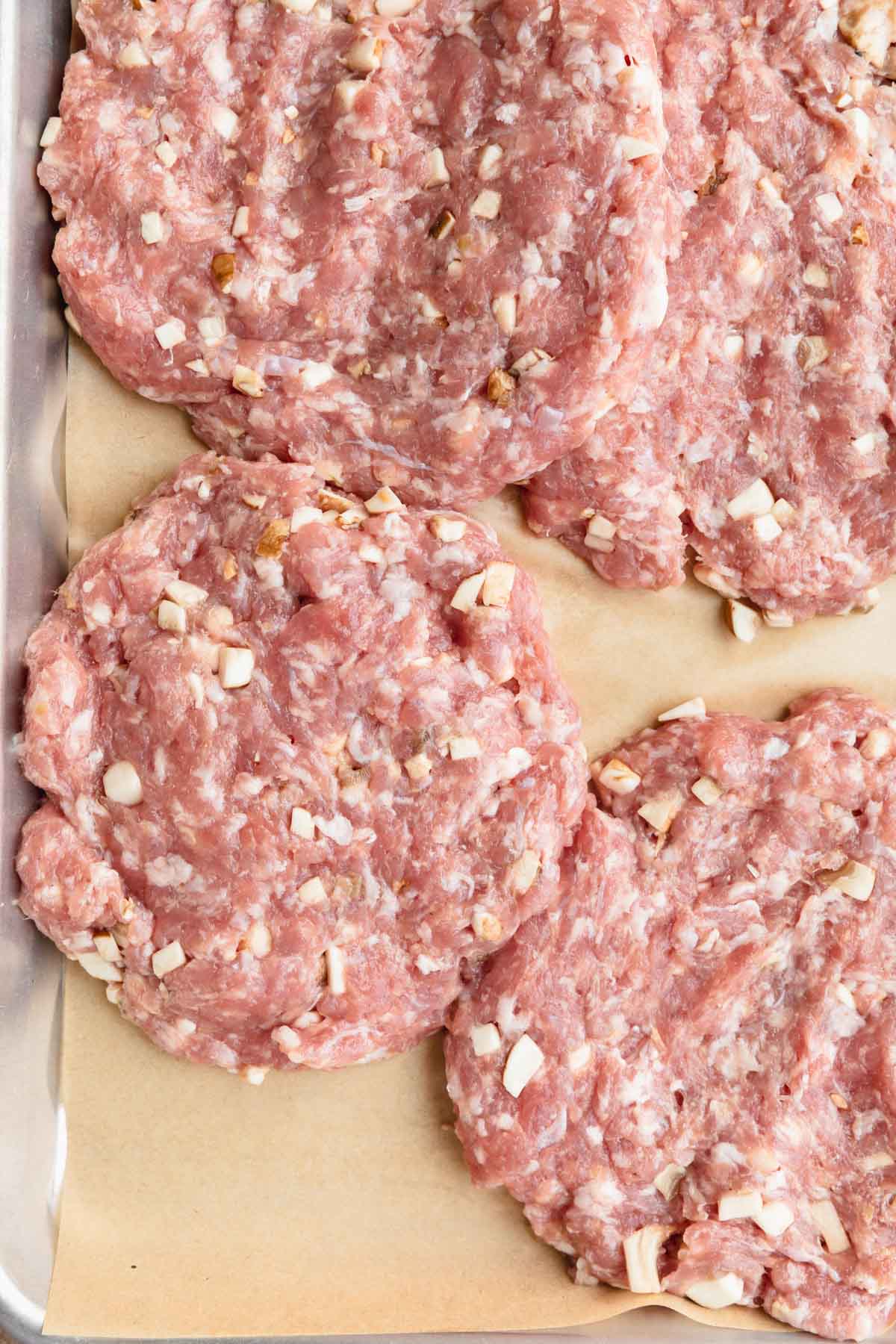 Pork burger patties on a sheet tray.