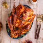 Dry Brined Roast Turkey with Citrus Butter Baste on serving platter at the table with wine and gravy.