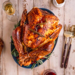 Dry Brined Roast Turkey with Citrus Butter Baste on serving platter at the table with wine and gravy.