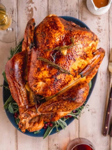 Dry Brined Roast Turkey with Citrus Butter Baste on serving platter at the table with wine and gravy.
