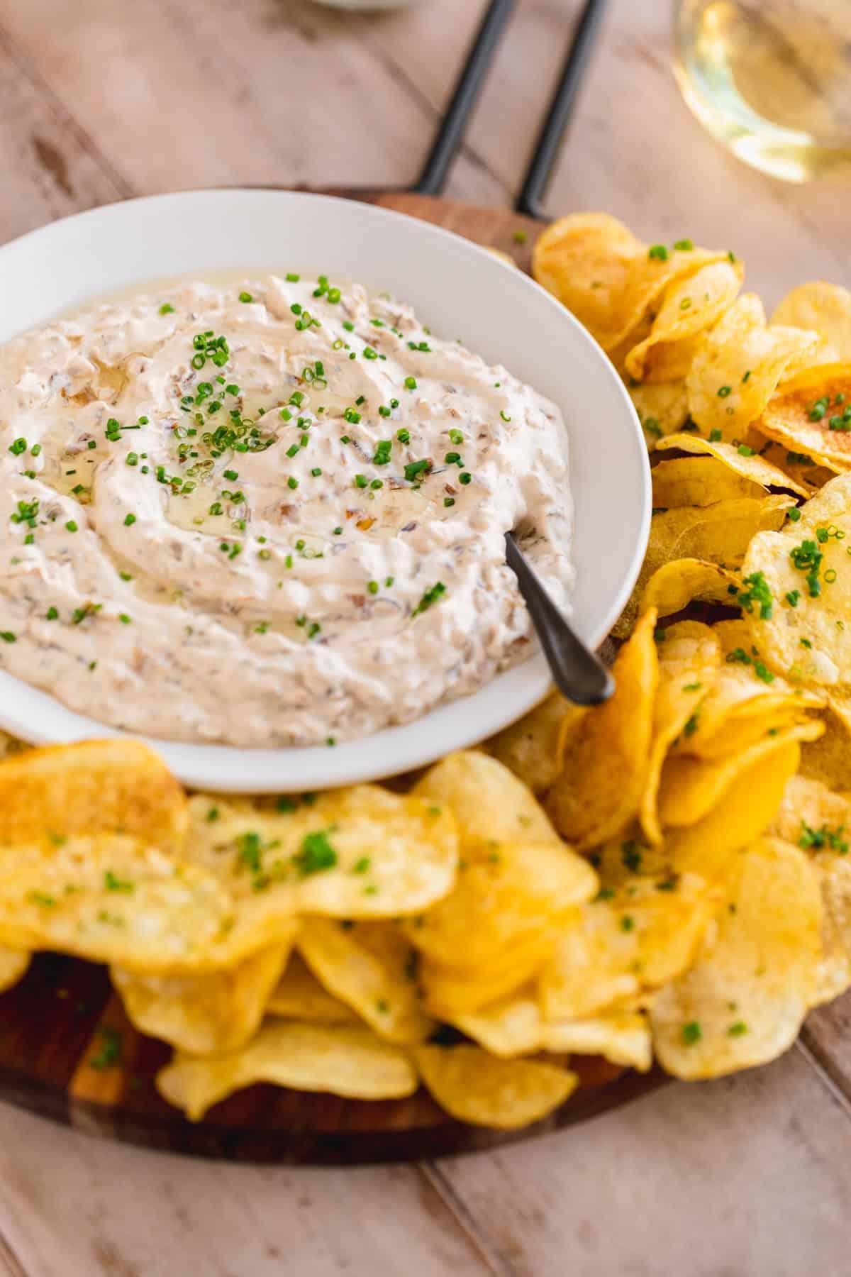 French Onion Dip in a serving bowl with potato chips surrounding it.