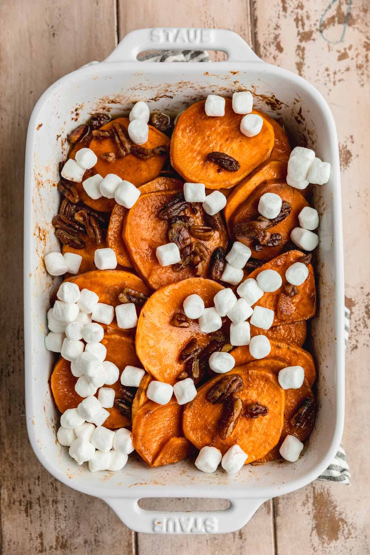 Cooked Sweet potatoes in a baking dish topped with marshmallows.