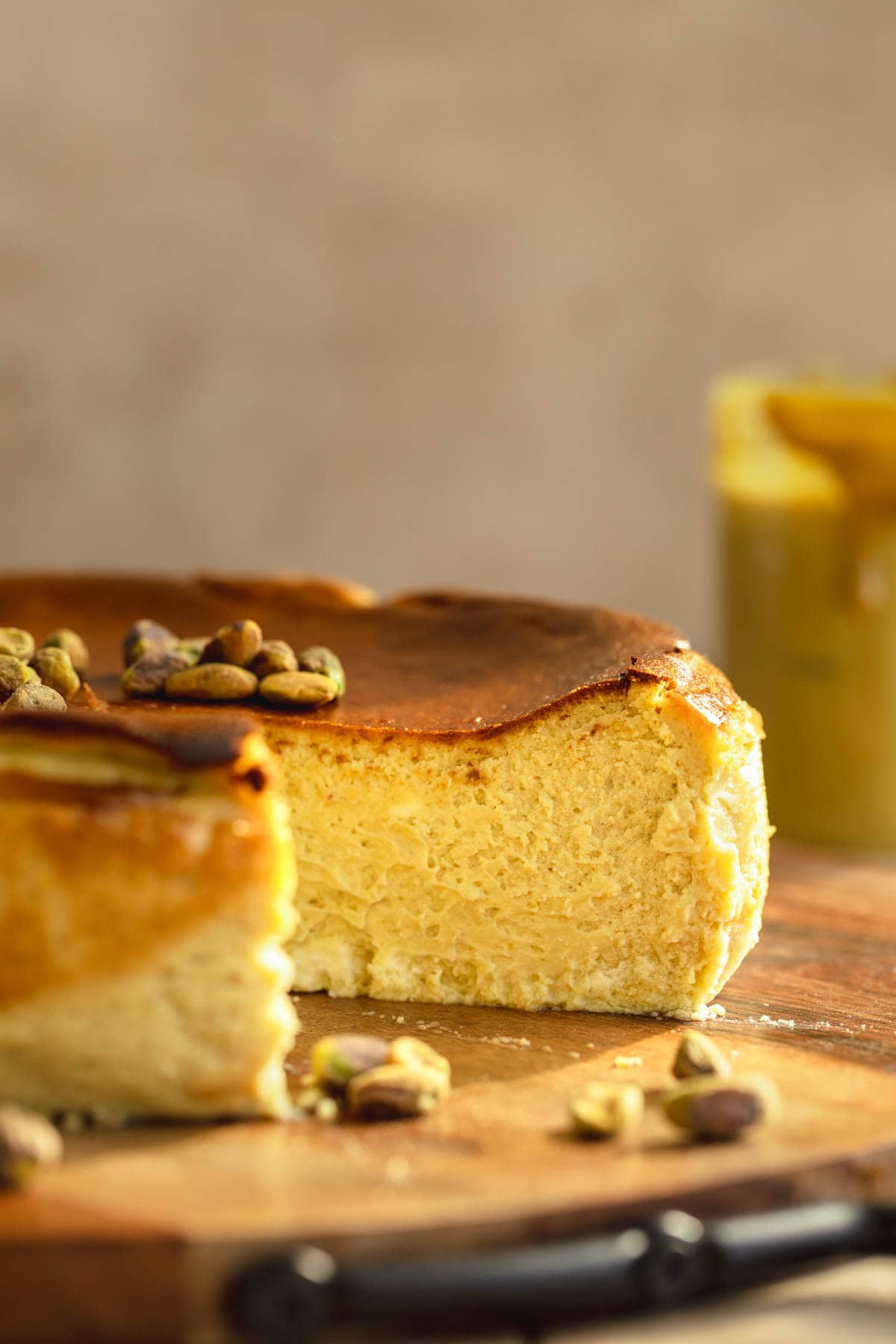 Basque Pistachio Cheesecake with a slice out of it on a serving board.