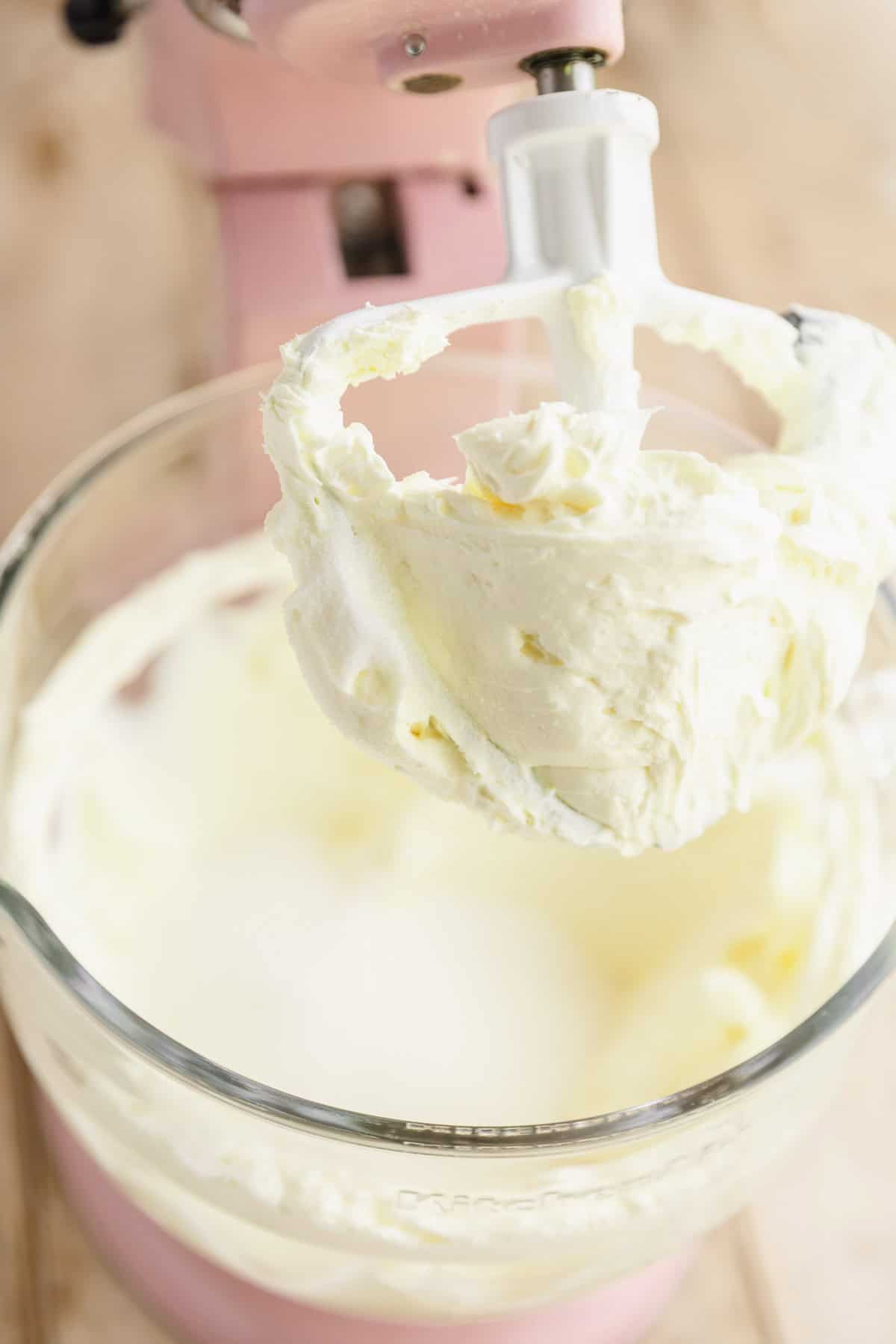 Cream cheese and sugar blended together in the bowl of a stand mixer.